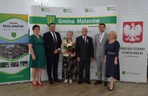 grupa osob pozuje na tle scianki z napisem gmina malanow (8)