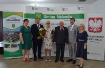 grupa osob pozuje na tle scianki z napisem gmina malanow (3)