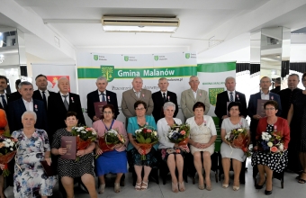 duza grupa osob stoi na tle scianki z napismi