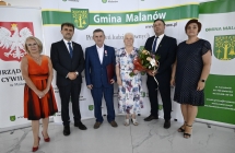 grupa osob stoi na tle scianki z napismi     