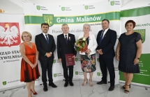 grupa osob stoi na tle scianki z napismi  