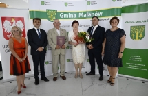 grupa osob stoi na tle scianki z napismi      