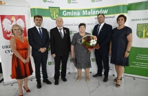 grupa osob stoi na tle scianki z napismi   