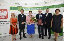grupa osob stoi na tle scianki z napismi        