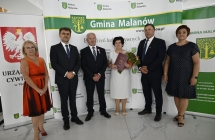 grupa osob stoi na tle scianki z napismi 